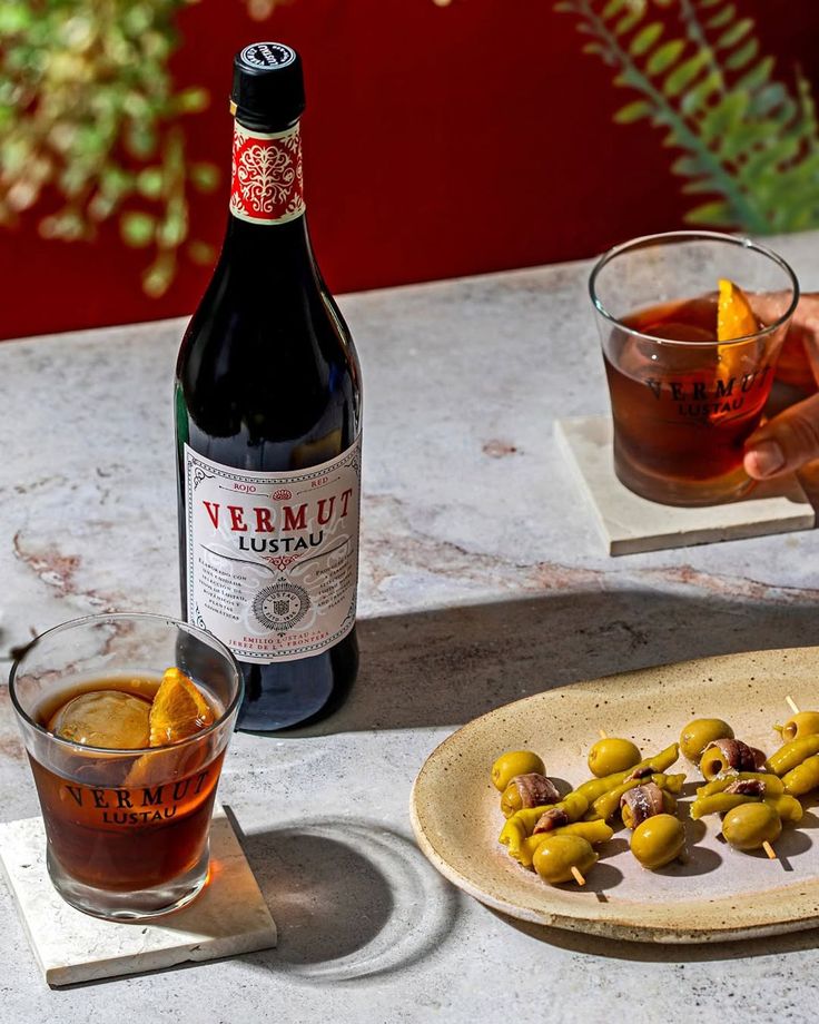 Verre de vermouth rouge avec une rondelle d'orange et une sélection de conserves d'anchois et sardines Miss Jamon
